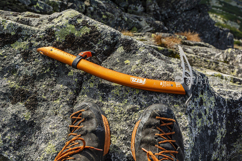 在您的秋季登山旅行中，Petzl Ride冰斧和Scarpa Mescalito在山顶的花岗岩卵石上接近靴子。